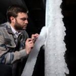 NASA Tests New Aircraft Wing for Critical Icing Conditions A man looks at white ice built up on a section of scale-model transonic truss-braced wing. The model wing stands vertically in NASA Glenn’s Icing Research Tunnel.