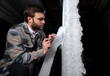 NASA Tests New Aircraft Wing for Critical Icing Conditions A man looks at white ice built up on a section of scale-model transonic truss-braced wing. The model wing stands vertically in NASA Glenn’s Icing Research Tunnel.
