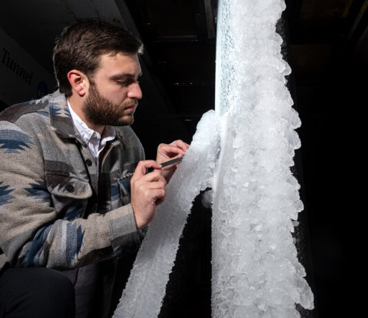 NASA Tests New Aircraft Wing for Critical Icing Conditions A man looks at white ice built up on a section of scale-model transonic truss-braced wing. The model wing stands vertically in NASA Glenn’s Icing Research Tunnel.