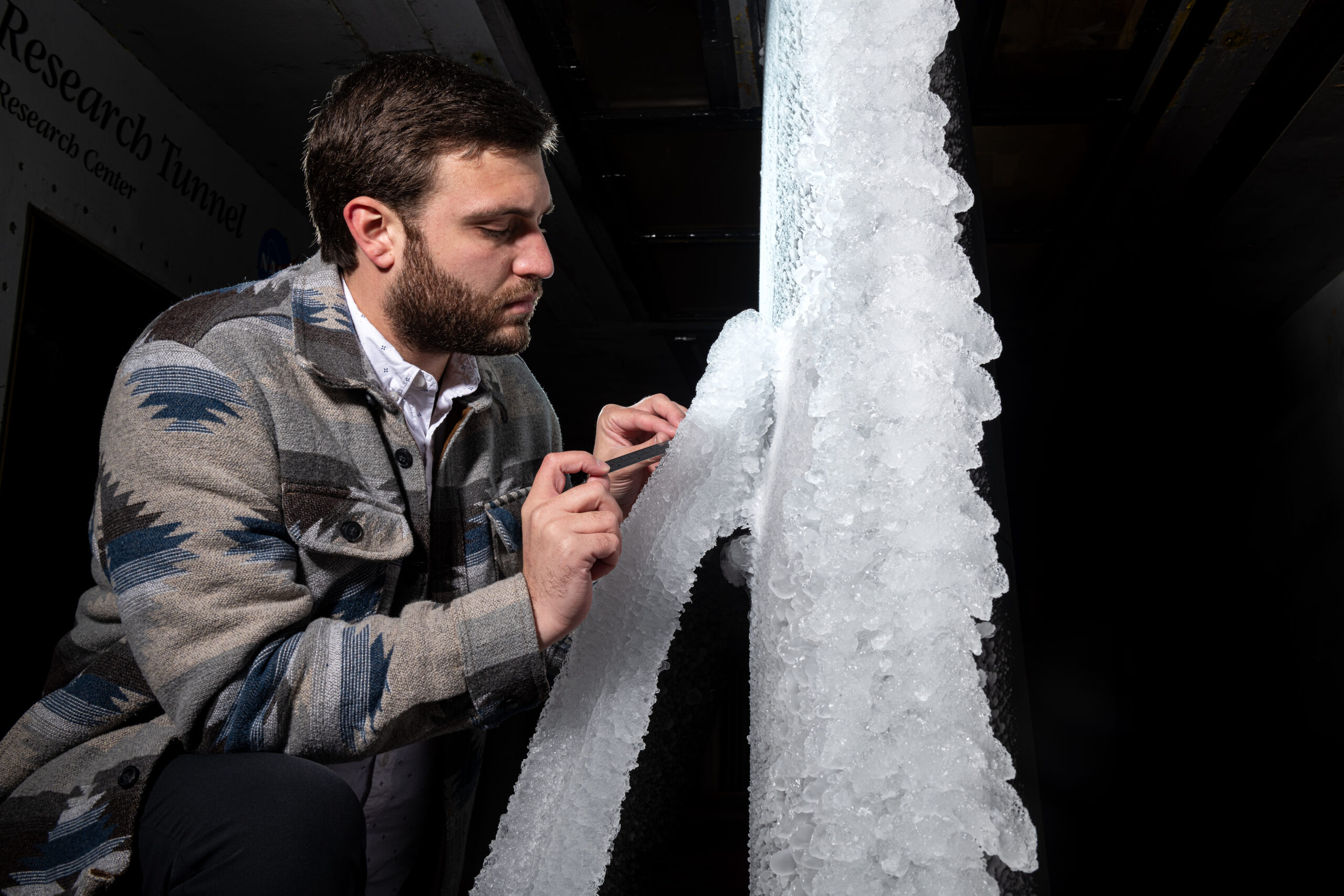 grc 2024 c 12100.jpg A man looks at white ice built up on a section of scale-model transonic truss-braced wing. The model wing stands vertically in NASA Glenn’s Icing Research Tunnel.