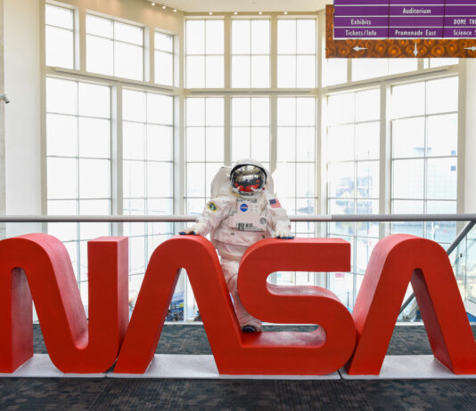 Ohio Space Week Festivities Held by NASA Glenn An astronaut mascot stands behind large red letters spelling out “NASA.”