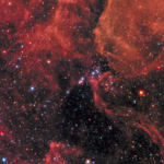 NASA Reveals Stunning Supernova Event Clouds of gas and dust in shades of red cover the top of the image and a little bit of the bottom. Right in the middle is Supernova 1987a, the remnant of an exploded star. The site of the supernova is surrounded by an illuminated pinkish ring. Two faint outer rings are also visible. Stars and galaxies shine throughout, giving off red and blue light.