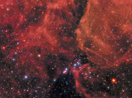 NASA Reveals Stunning Supernova Event Clouds of gas and dust in shades of red cover the top of the image and a little bit of the bottom. Right in the middle is Supernova 1987a, the remnant of an exploded star. The site of the supernova is surrounded by an illuminated pinkish ring. Two faint outer rings are also visible. Stars and galaxies shine throughout, giving off red and blue light.