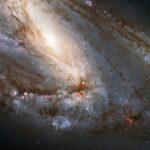 NASA Explores Celestial Wonders in the Leo Constellation A spiral galaxy is viewed sideways, with the glowing core closer to the upper left of the image. It is surrounded by spiral arms laced through with dark dust and bright regions of star formation.