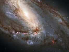 NASA Explores Celestial Wonders in the Leo Constellation A spiral galaxy is viewed sideways, with the glowing core closer to the upper left of the image. It is surrounded by spiral arms laced through with dark dust and bright regions of star formation.