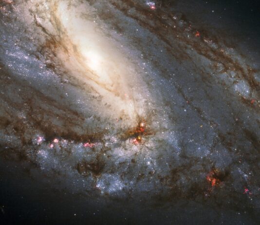 NASA Explores Celestial Wonders in the Leo Constellation A spiral galaxy is viewed sideways, with the glowing core closer to the upper left of the image. It is surrounded by spiral arms laced through with dark dust and bright regions of star formation.