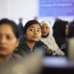 Indians Embrace AI Training for Professional and Personal Growth A group of young women look up from their computer screens.