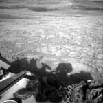 NASA Science Explores Skies: Curiosity Blog Sols 4577-4579 A grayscale photograph from the Martian surface shows rough terrain covered in a multitude of small- to medium-sized rocks, resting atop timeworn surface features, all colored a fairly light gray. Part of the Curiosity rover, and a shadow it is casting, are visible at the bottom of the frame.