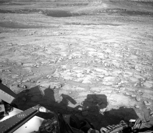 NASA Science Explores Skies: Curiosity Blog Sols 4577-4579 A grayscale photograph from the Martian surface shows rough terrain covered in a multitude of small- to medium-sized rocks, resting atop timeworn surface features, all colored a fairly light gray. Part of the Curiosity rover, and a shadow it is casting, are visible at the bottom of the frame.