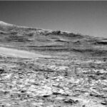NASA Science Explores Vast Martian Terrain: Curiosity Blog Update A grayscale photo from the Martian surface shows rocky ground from the front of the image to a horizon line where a series of gently sloped hills rise up.