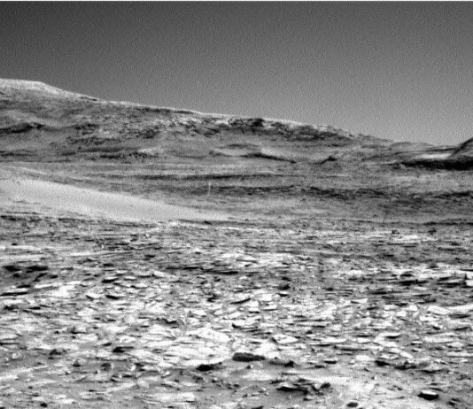 NASA Science Explores Vast Martian Terrain: Curiosity Blog Update A grayscale photo from the Martian surface shows rocky ground from the front of the image to a horizon line where a series of gently sloped hills rise up.