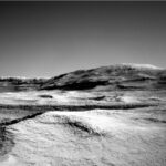 NASA Curiosity: Exploring Martian Atmosphere on Sols 4604-4606 A grayscale photo from the Martian surface shows a landscape of undulating but mostly smooth terrain from the front of the image to a gently sloping hill that rises from the center of the image toward the upper right side of the frame. Beyond that, a straight ridge creates a horizon line along the left side of the image, disappearing from sight behind the hill.