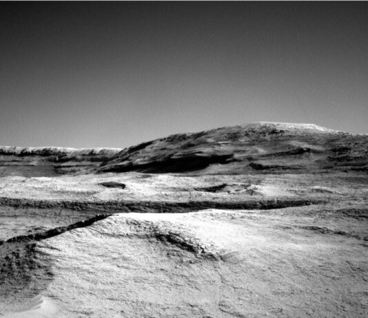 NASA Curiosity: Exploring Martian Atmosphere on Sols 4604-4606 A grayscale photo from the Martian surface shows a landscape of undulating but mostly smooth terrain from the front of the image to a gently sloping hill that rises from the center of the image toward the upper right side of the frame. Beyond that, a straight ridge creates a horizon line along the left side of the image, disappearing from sight behind the hill.