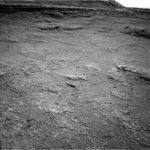 Curiosity Blog Sols 4609–4610: Powered Up for Further Exploration A grayscale photo from the Martian surface shows rough, slightly uneven, dark gray, rocky terrain extending to a plateau that rises in the distance, at the top of the frame. In the foreground, many smaller rocks are poking above the surface, much lighter-toned than the surrounding ground, looking like white specks on the surface.