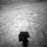 Curiosity Begins Year 14 Studying Martian Veins A grayscale photo from the Martian surface shows a rough, rocky landscape in medium gray, with a shadow of the Curiosity rover’s boxy masthead showing at the bottom center of the frame.