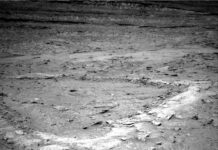 Curiosity Explores Boxworks: Choosing Next Dig Site, Sols 4675-4681 A grayscale photo from the Martian surface shows a landscape with an elevated ridge running from the foreground, at the bottom left of the image, toward the middle right side of the frame, with two branches extending toward the left side of the frame, creating a U-shaped depression between them. The top of the ridge is much lighter colored than the medium gray surrounding terrain, which extends off to the horizon at the top of the frame, and is interspersed with areas of scattered small, jagged rocks and wavy sand deposits.