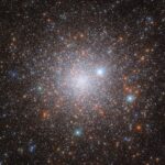 NASA’s Hubble Uncovers Ancient Galactic Relic A cluster of stars in space. It’s bright in the center, where the stars are densely packed together in the cluster’s core and grows dimmer and more diffuse out to the edges, as the stars give way to the dark background of space. A few orange stars are spread across the cluster, but most are pale, bluish-white points of light. Three large stars with cross-shaped diffraction spikes around them lie between us and the cluster.