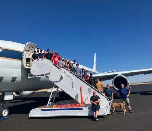 Retired DC-8 Aircraft Inspires Students Beyond Textbooks – NASA A group of 22 students pose on a stairway descending from an aircraft door. The plane and stairway are white, on a sunny tarmac.