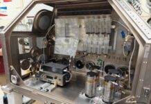 NASA Develops Technology to Produce IV Fluids in Space A large metal housing box containing the IVGEN Mini system is set up to create IV fluid. It includes the filtering system (two small boxes with cords attached), one plastic input bag, one plastic output bag, 10 syringes, additional cording, and four silver cylinder-shaped pieces of equipment.