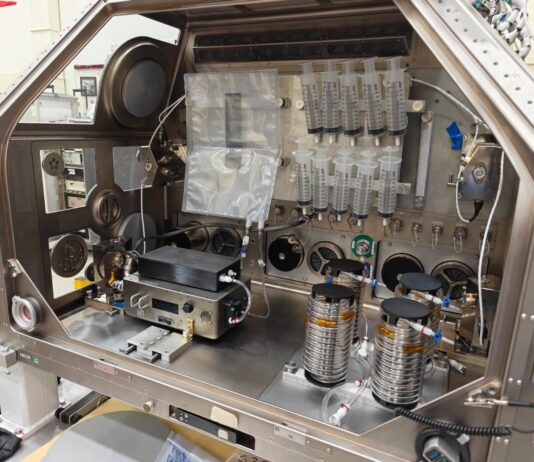 NASA Develops Technology to Produce IV Fluids in Space A large metal housing box containing the IVGEN Mini system is set up to create IV fluid. It includes the filtering system (two small boxes with cords attached), one plastic input bag, one plastic output bag, 10 syringes, additional cording, and four silver cylinder-shaped pieces of equipment.