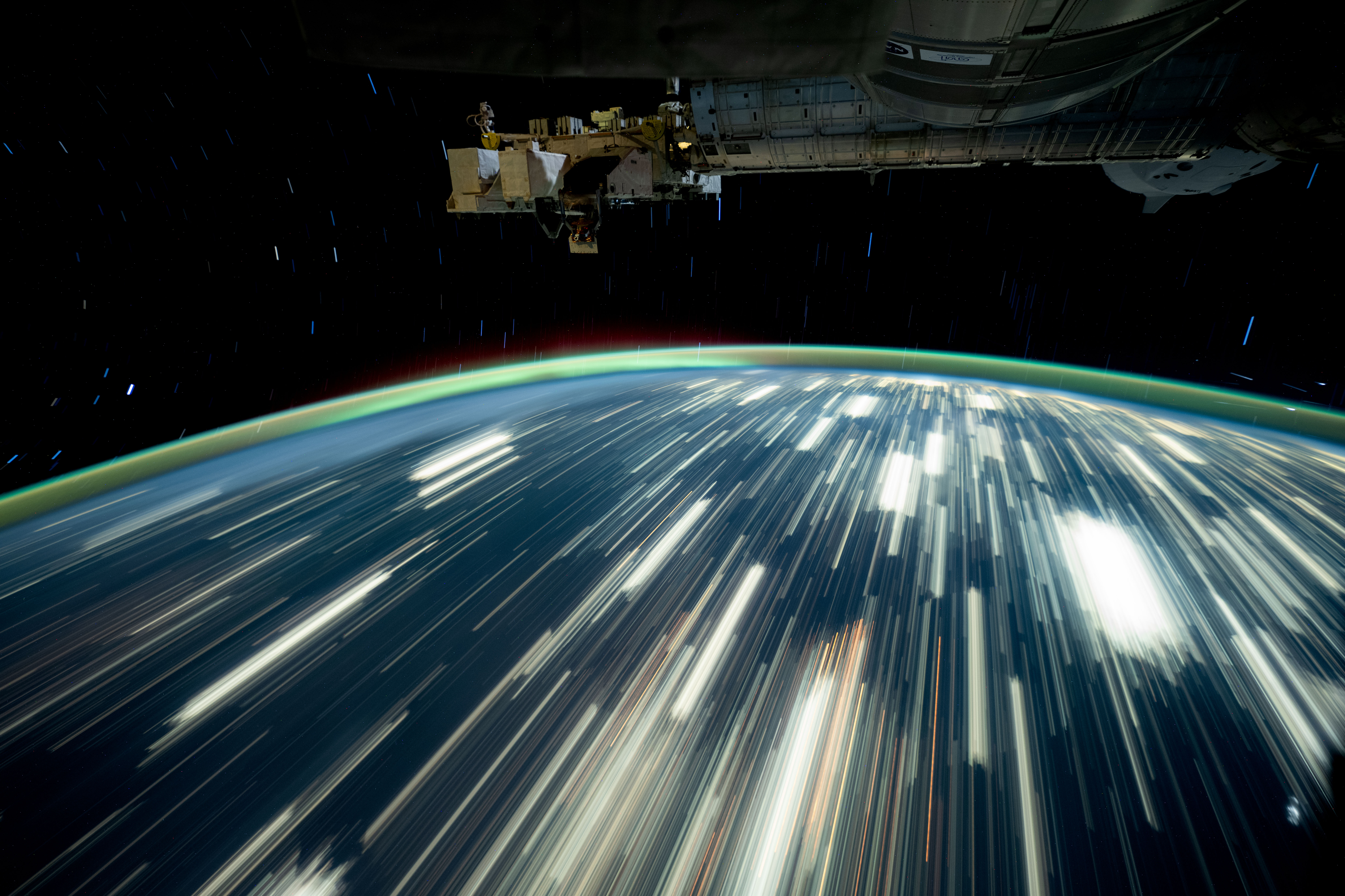 City lights on Earth appear as bright streaks in this long-exposure photo. Earth