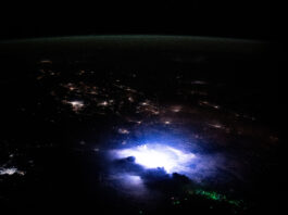 NASA Explores Lightning Phenomena in Southeast Asia Southeast Asia occupies the bottom two-thirds of the image. The scene is dark except for nighttime lights coming from urban areas, the white and purple glow from a thunderstorm, and green dots from fishing boats. A strip of green airglow is visible across the planet