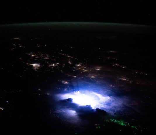 NASA Explores Lightning Phenomena in Southeast Asia Southeast Asia occupies the bottom two-thirds of the image. The scene is dark except for nighttime lights coming from urban areas, the white and purple glow from a thunderstorm, and green dots from fishing boats. A strip of green airglow is visible across the planet