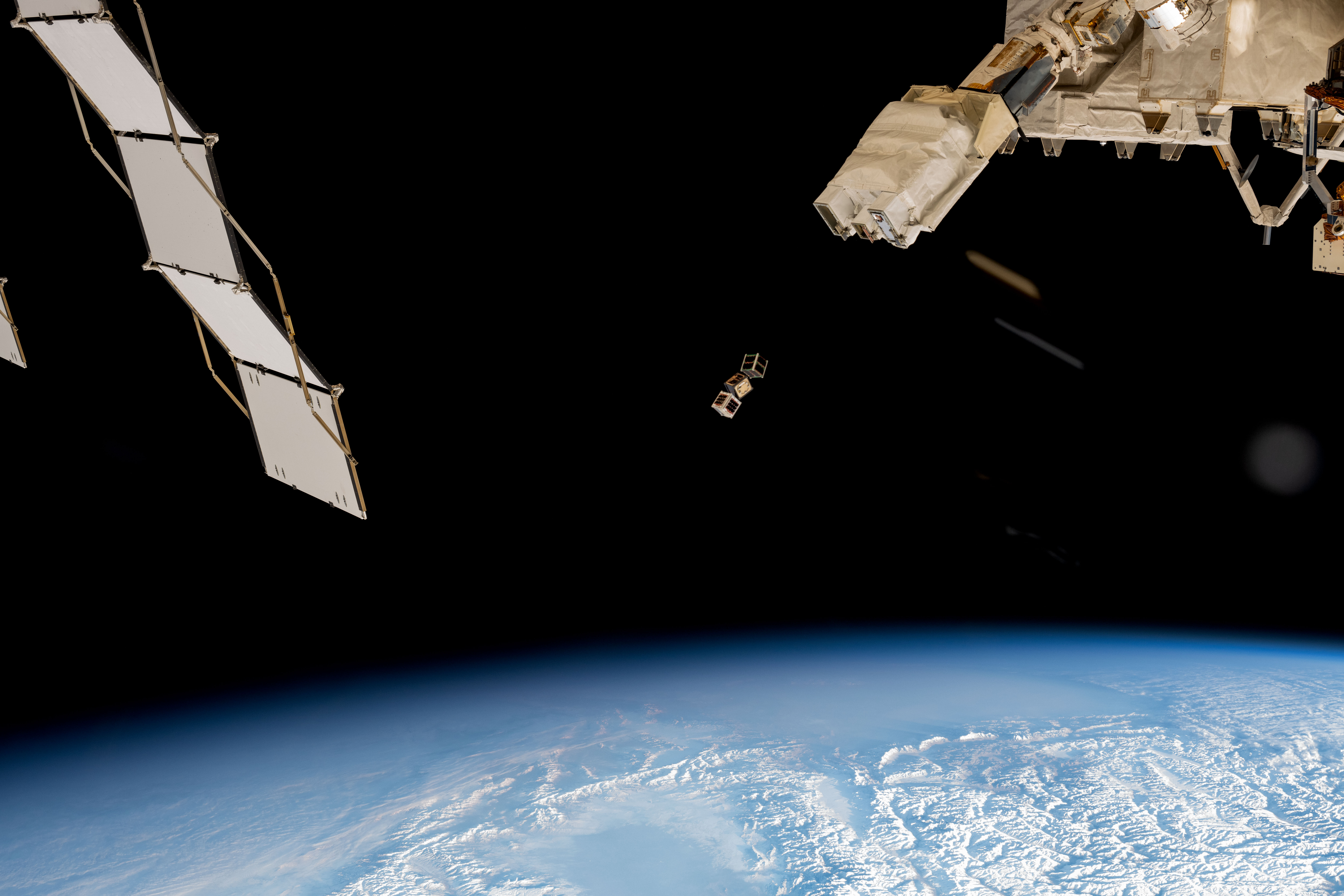 iss072e352043.jpg An outside view of the space station with three square boxes in the center of the image. To the left is a solar panel. To the right is part of the space station. At the bottom is a view of the Earth.