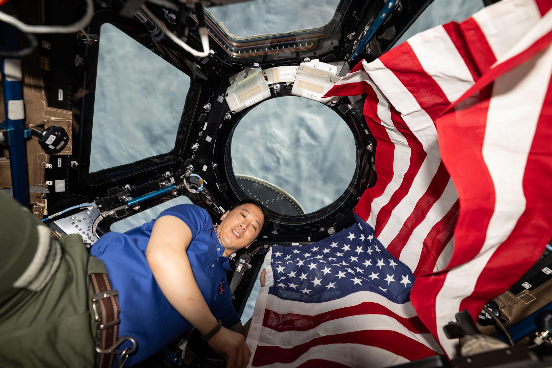 NASA astronaut and Expedition 73 Flight Engineer Jonnny Kim poses for a portrait with the American flag on the Fourth of July, or Independence Day, inside the International Space Station