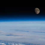NASA Highlights Waxing Gibbous Moon Phase The Moon is nearly full and a deep gray-brown color in this image. Below it is Earth’s blue atmosphere and and white clouds. This photo was taken from the International Space Station.