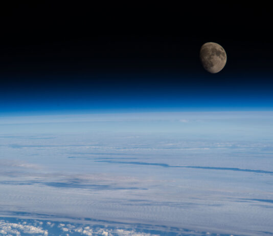 NASA Highlights Waxing Gibbous Moon Phase The Moon is nearly full and a deep gray-brown color in this image. Below it is Earth’s blue atmosphere and and white clouds. This photo was taken from the International Space Station.