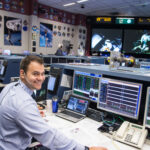 Brian Alpert Leverages Experience for Artemis Moon Mission Success A man wearing a headset sits at a computer console in the Mission Control Center at Johnson Space Center.