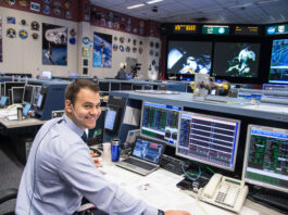 Brian Alpert Leverages Experience for Artemis Moon Mission Success A man wearing a headset sits at a computer console in the Mission Control Center at Johnson Space Center.