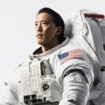 Astronaut Jonny Kim Talks Future Mission and Launch Plans NASA astronaut Jonny Kim looks off-camera, dressed in a white space suit with an American flag on the sleeve.