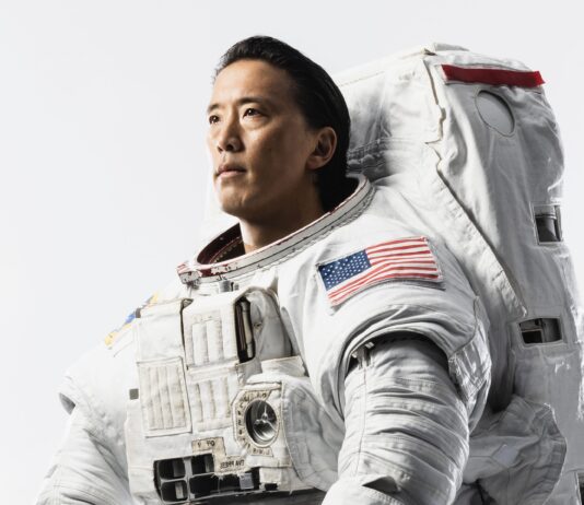 Astronaut Jonny Kim Talks Future Mission and Launch Plans NASA astronaut Jonny Kim looks off-camera, dressed in a white space suit with an American flag on the sleeve.