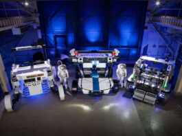 NASA Evaluates Commercial Rovers for Upcoming Lunar Missions Three lunar terrain vehicles side by side inside of a large chamber with dramatic lighting. Astrolab