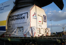 NASA Celebrates Arrival of HALO Module for Lunar Gateway A large cargo aircraft with its nose lifted open reveals a wrapped container being offloaded. The container is marked with the logo for NASA