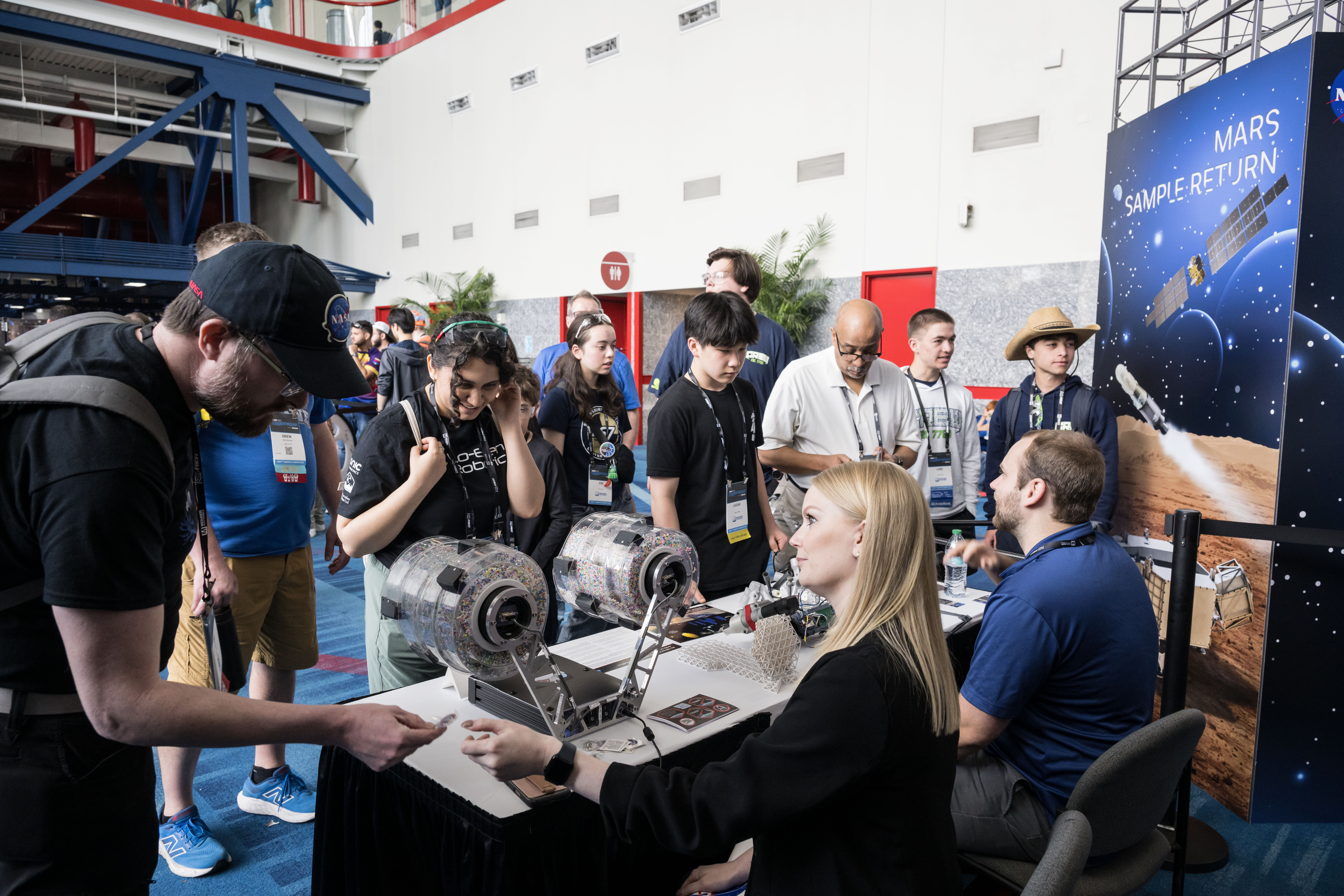 jsc2025e039509.jpg Two people sit at a booth with space exploration materials. They are engaging with the public at an event.
