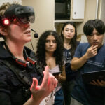 Student Teams Conclude NASA Space Suit Challenge Successfully A woman wears a virtual reality headset with three people observing behind her.
