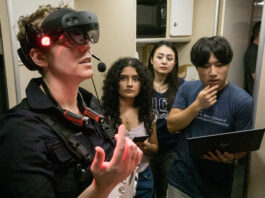 Student Teams Conclude NASA Space Suit Challenge Successfully A woman wears a virtual reality headset with three people observing behind her.