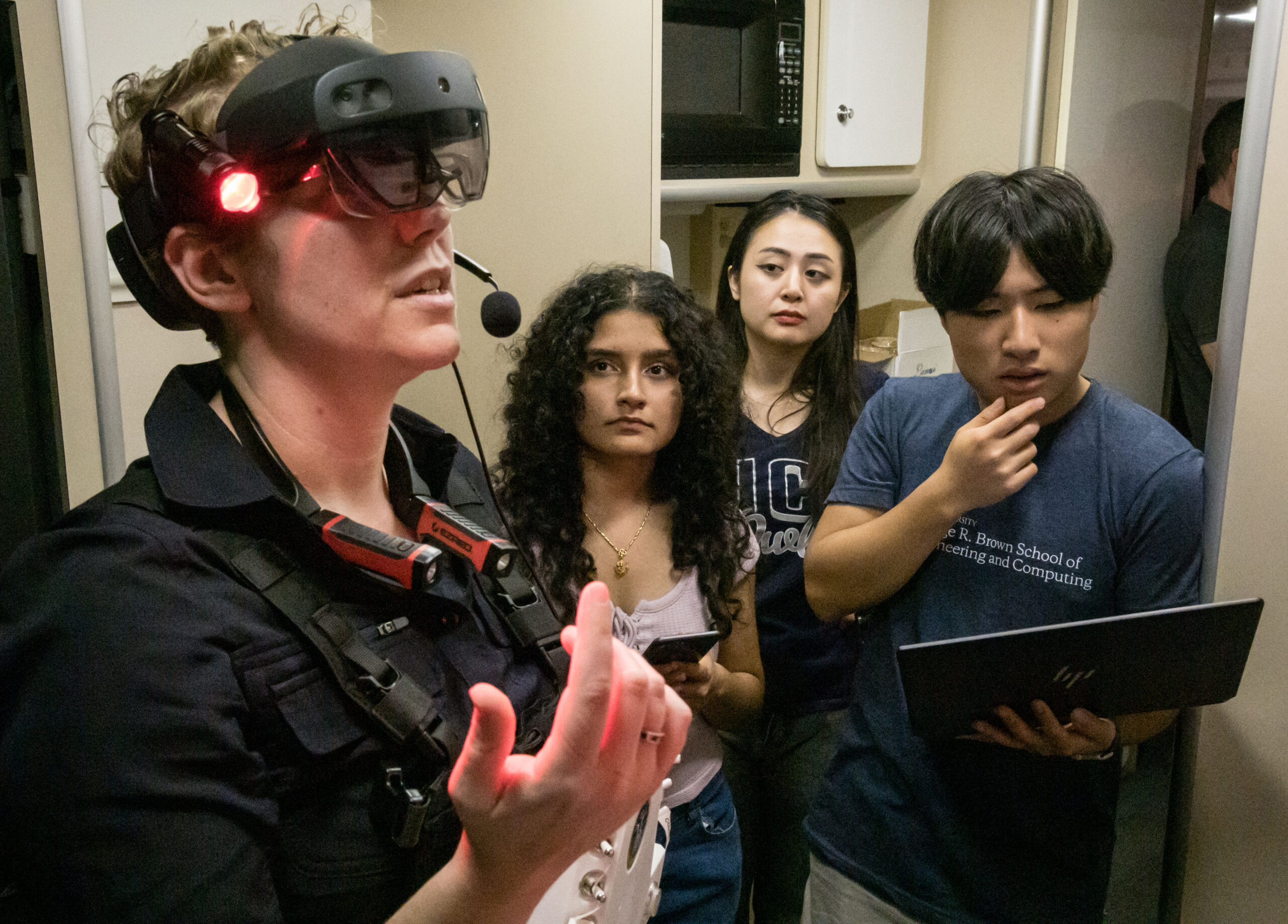 jsc2025e046436.jpg A woman wears a virtual reality headset with three people observing behind her.