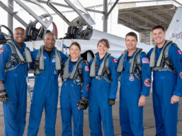 Artemis II Crew Receives NASA Farewell Before Mission Departure From left to right, NASA astronauts Andre Douglas, Victor Glover, and Christina Koch, CSA (Canadian Space Agency) astronauts Jenni Gibbons, NASA astronaut Reid Wiseman, and CSA astronaut Jeremy Hansen pose in front of an airplane. They are all wearing blue jumpsuits with patches and gray harnesses.