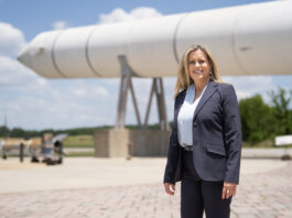 Meet Julia Khodabandeh: NASA’s Artemis Program Star A blonde woman stands in front of a rocket booster in a grey jacket.