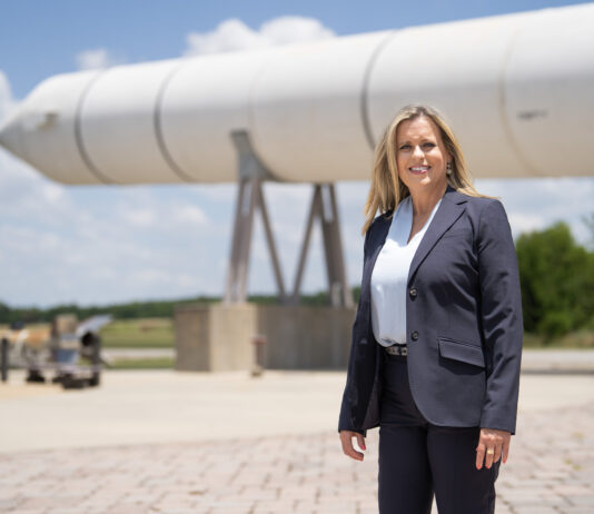 Meet Julia Khodabandeh: NASA’s Artemis Program Star A blonde woman stands in front of a rocket booster in a grey jacket.