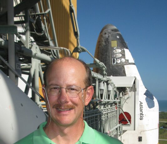 Michael Ciancone Leaves Enduring Impact on Human Spaceflight at NASA A man wearing a neon green polo smiles outside on a sunny day in front of a space shuttle.