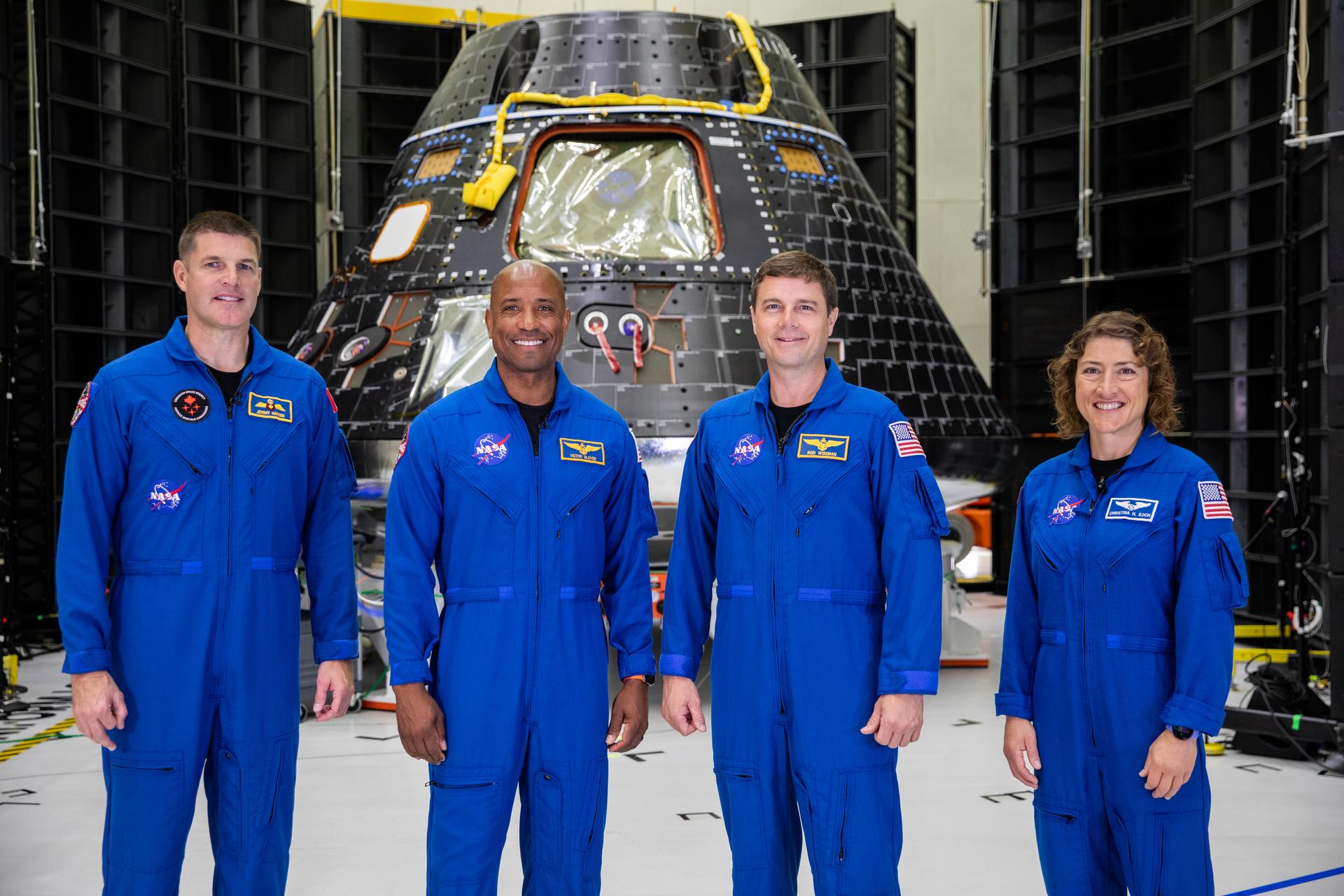 ksc 20230808 ph kls02 0098large.jpg Four Artemis II astronauts in their blue flight suits stand smiling in front of a cone-shaped black-and-silver Orion spacecraft.