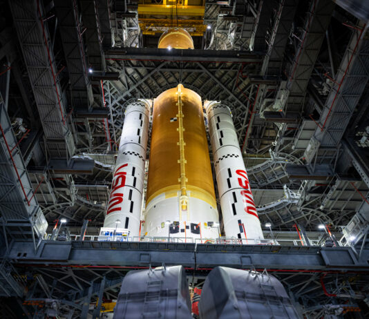 NASA Completes Artemis II Core Stage Integration The Artemis II core stage (a butterscotch orange cylinder in the middle) and solid rocket boosters (the white cylinders, branded with the NASA