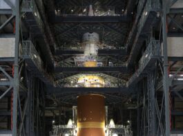 NASA Completes Artemis II Orion Spacecraft Stacking The orange core stage of the Artemis II rocket with white boosters on each side fully stacked inside the Vehicle Assembly Building at NASA