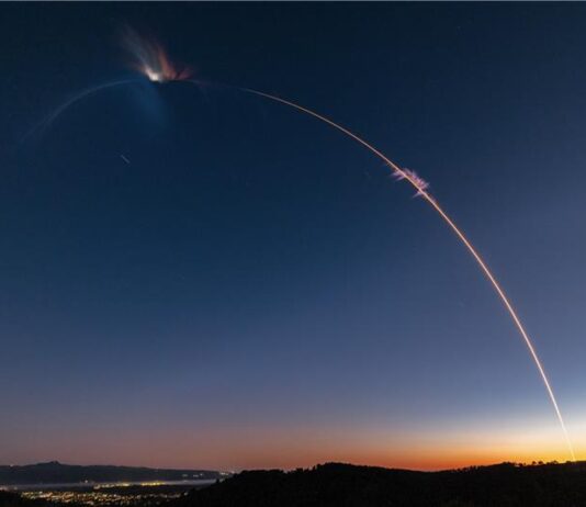 Firefly Aerospace Launches Eight NASA CubeSats into Space! A photo taken with extended exposure shows the streak of light made by a rocket in a twilight sky. City lights are below on the left and the horizon has an orange glow where the sun has set in the lower right.
