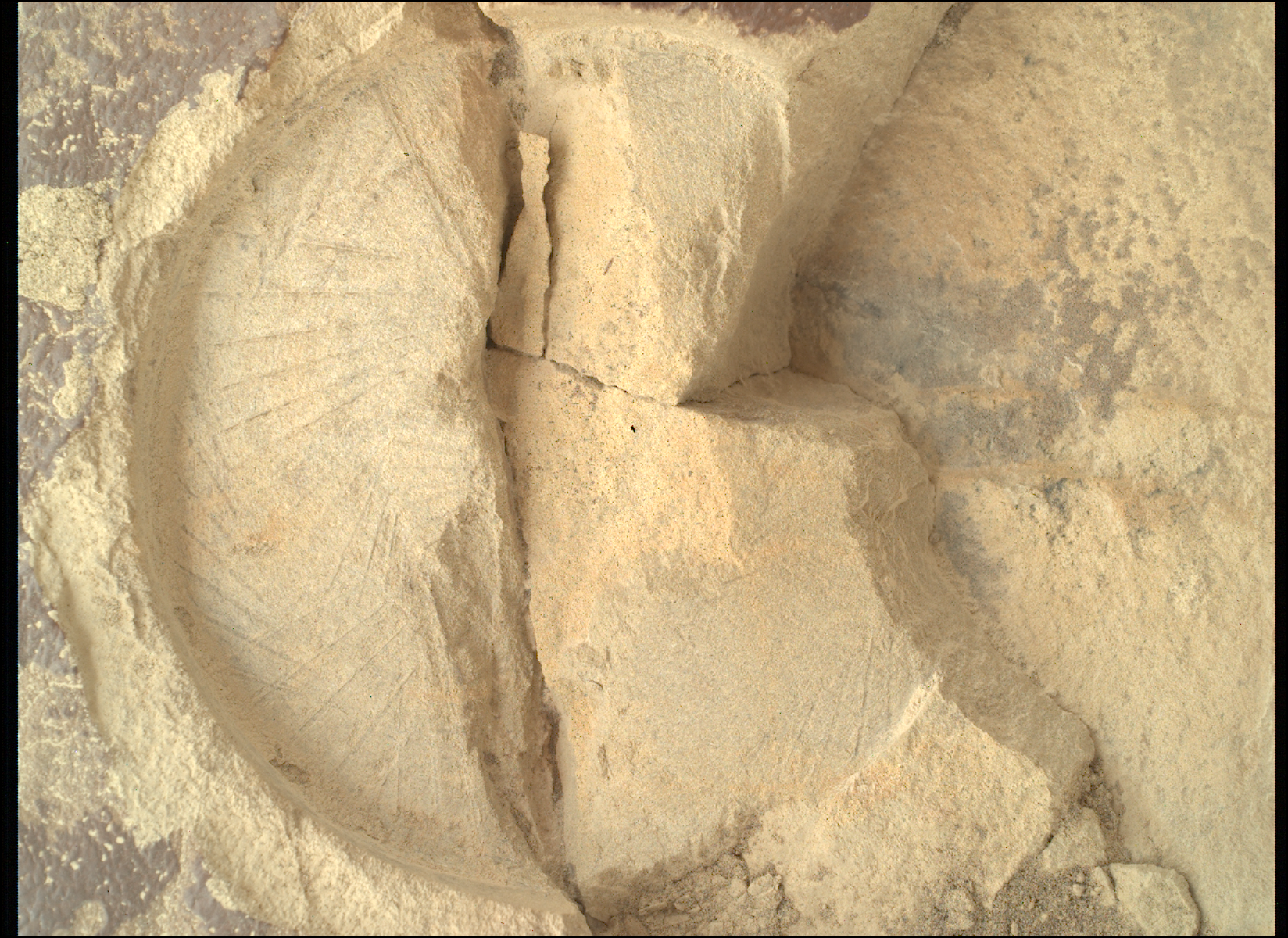 mars perseverance sif 1436 0794428005 417eby n0692124srlc01037 0000lmj.png A color close-up photo from the Martian surface shows a circular impression on the flat, hard-looking stone surface, colored brownish-tan, which takes up almost all the image frame. The impression dimensions — its depth compared to its circumference — resembles that of a pie tin. The color of the terrain exposed in the impression is a pale warm tan, much lighter than the surrounding rock. The impression is fractured, in a crack straight down its middle. Another small crack points from the center toward the 4 o’clock position in the circle. To the right of that, the rest of the circle is cleaved off, and the entirety of about one-third of the right side of the circle is missing past a zig-zag line, running from about 1 o’clock to 5 o’clock, leaving an edge that descends below the surface, about twice the depth of the original impression.